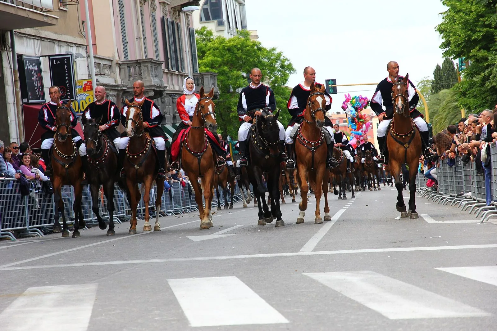 Cavalieri in costume tradizionale sardo sfilano a cavallo lungo un viale di Sassari durante la Cavalcata Sarda