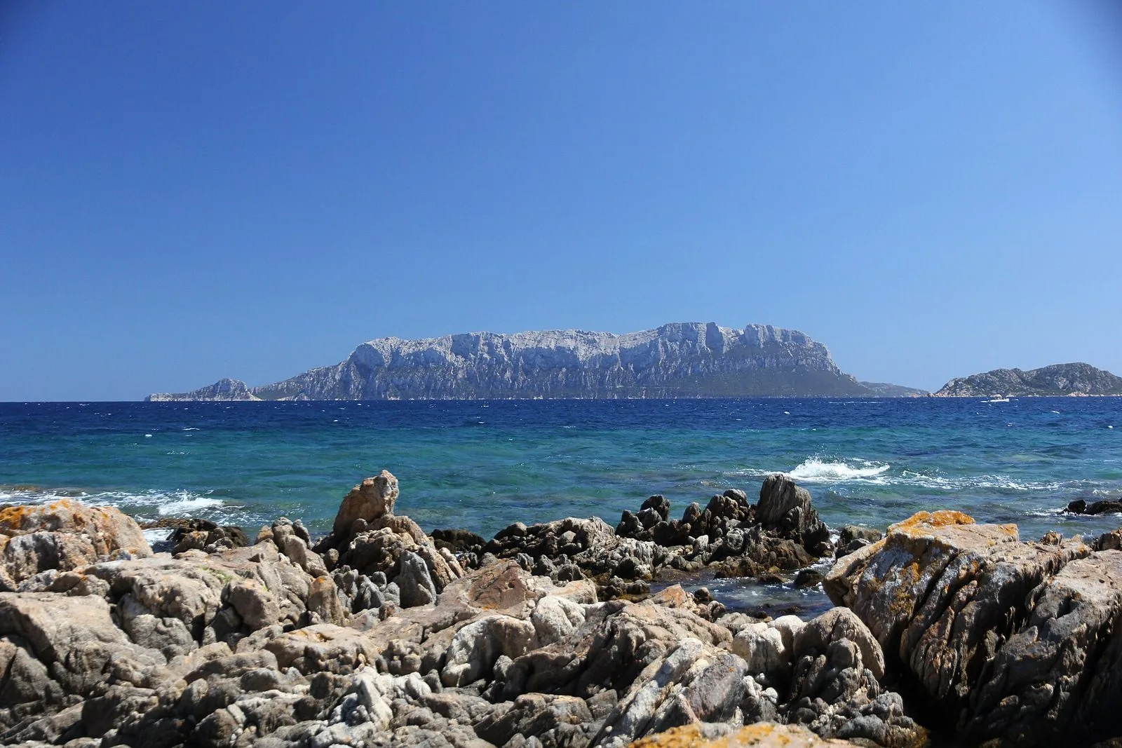 L'isola di Tavolara vista dalla costa rocciosa, con il mare turchese in primo piano