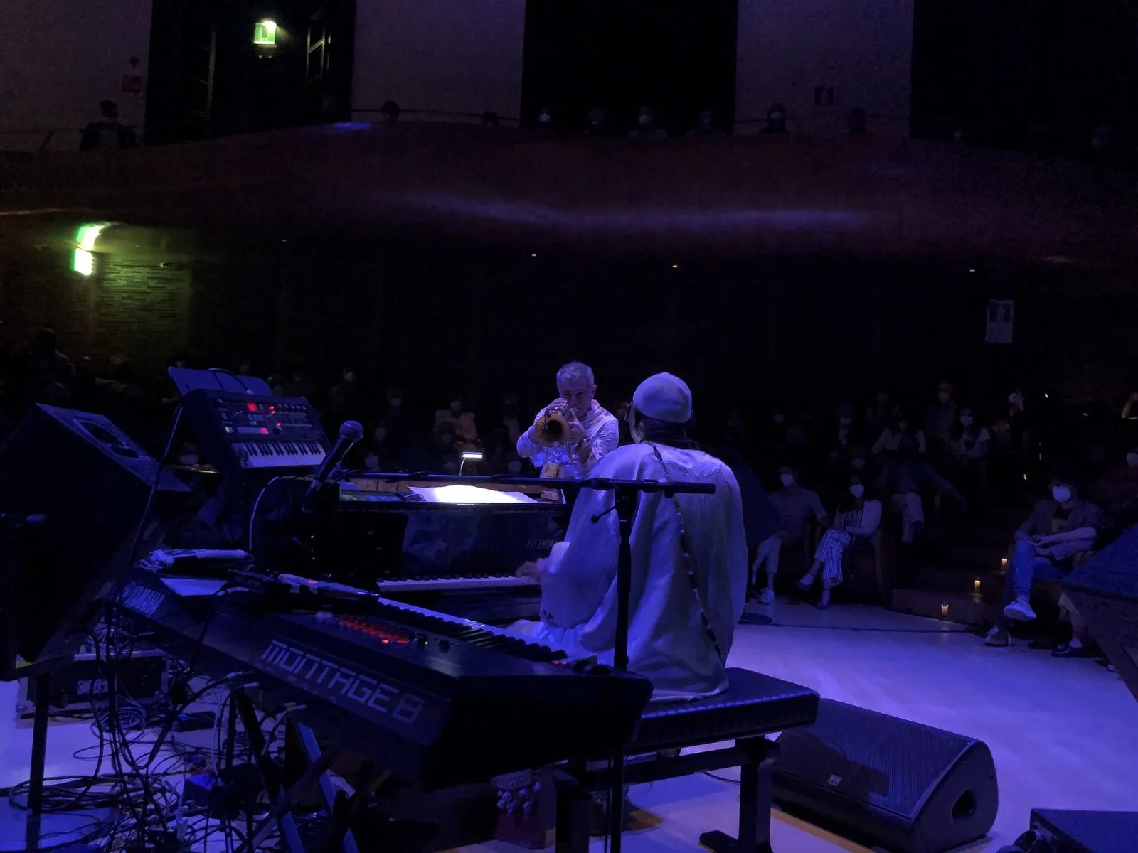 Paolo Fresu suona la tromba sul palco durante un concerto con il pianista Omar Sosa, in una sala in penombra